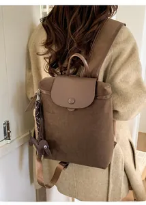 Detail of dark brown canvas backpack with leather flap and a cute dachshund charm
