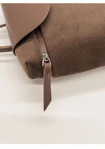 Close-up of premium textured canvas bag with smooth leather flap and silver zipper detail