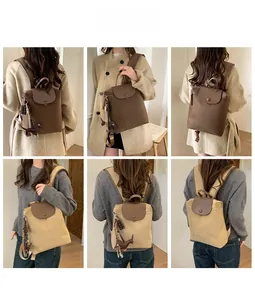 Detail of canvas backpack with leather flap showing model styling and dog charm accessory