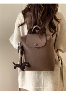 Detail of minimalist retro brown backpack with cute dachshund charm and leather straps