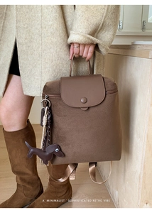 Close-up of retro brown canvas backpack with leather flap and dachshund charm