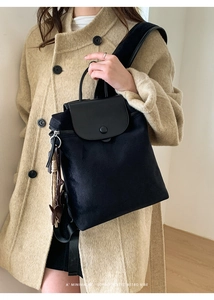 Close-up of black velvet backpack with leather flap and retro tassel charm detail