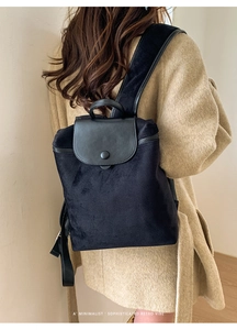 Black retro backpack in suede and leather shown on a model with a beige coat