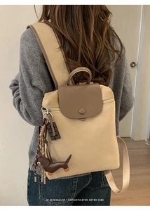 Rear view of model wearing a minimalist khaki canvas backpack with dark leather trim