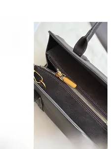 Close-up of smooth gold metal zipper closure on a vintage dark grey suede crossbody bag