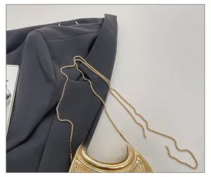 Détail du sac de soirée doré avec poignée ronde en métal et fine bandoulière chaîne