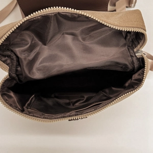 Detailed interior of khaki canvas backpack showing zipper pocket and spacious lining