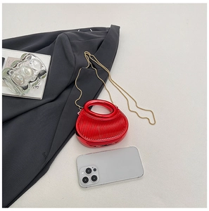 Détail d'un mini sac de soirée rouge texturé avec chaîne dorée et poignée intégrée