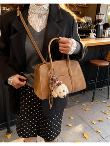 Brown vintage suede shoulder bag styled with a cute puppy pendant and elegant black coat