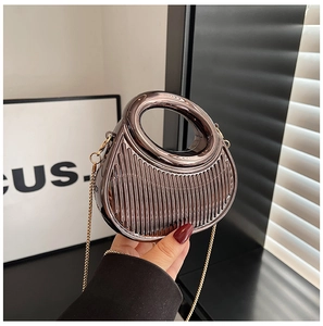 Détail d'un mini sac argenté avec rayures verticales et bandoulière dorée