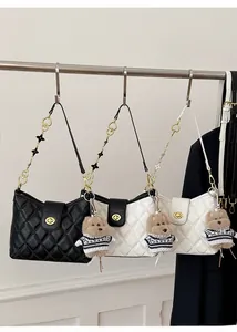 Close-up of quilted crossbody bag with heart chain strap and cute teddy bear charm