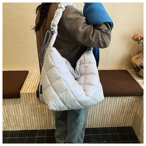 Detail of oversized quilted puffer shoulder bag in light blue-grey with wide strap