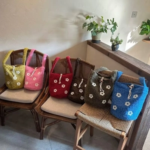 Detail of colorful crochet flower bucket bags with drawstring and floral embroidery