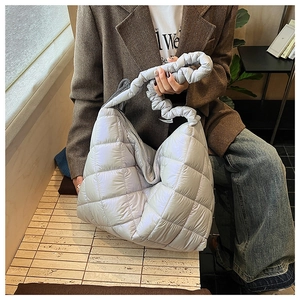 Detail of lavender quilted puffer bag featuring a unique ruched strap and square stitching