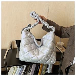 Macro detail of silver quilted puffer shoulder bag with stylish ruched handle design