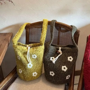 Detailed close-up of floral embroidery on handmade crochet plush bucket bags with wood buttons