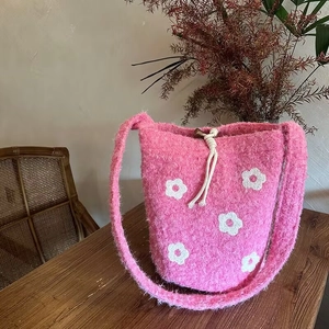 Close-up of pink plush bucket bag with white flower embroidery and drawstring detail
