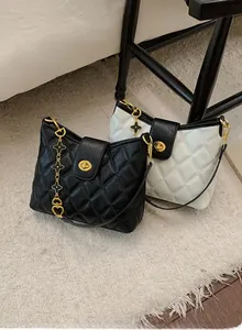 Detail of quilted leather handbag with gold twist lock and clover charm chain strap