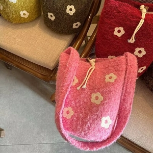 Close-up of handmade knitted floral drawstring bags in assorted retro autumn colors