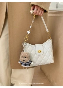 Detail of white quilted crossbody bag with gold chain and floral heart charms