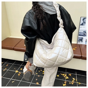 Close-up of beige quilted hobo bag with cloud-style ruched shoulder strap and metallic finish