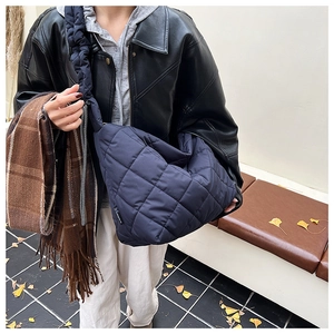 Close-up of navy blue quilted puffer bag featuring a unique ruched wide shoulder strap