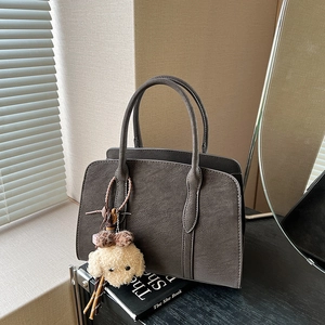 Minimalist taupe suede shoulder bag with cute teddy dog pendant on lifestyle background