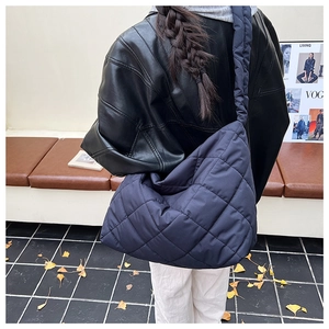 Detail of dark blue quilted shoulder bag with diamond stitching in a cozy autumn setting