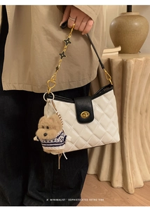 Detail of white quilted crossbody bag with golden chain and plush puppy charm accessory