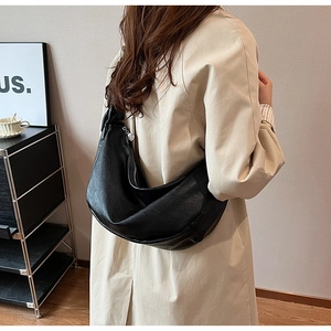 Detailed close-up of large black pebbled leather half-moon bag on shoulder