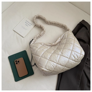 Detail of quilted shoulder bag featuring cream rhombic stitching and ruched cloud strap