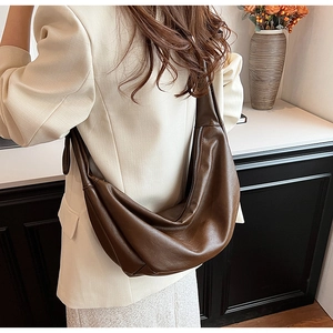 Gros plan d'un sac hobo demi-lune marron foncé avec texture cuir et fermeture éclair argentée