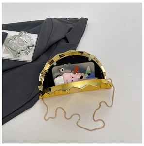 Detailed interior of a golden fan-shaped evening clutch with black lining and chain