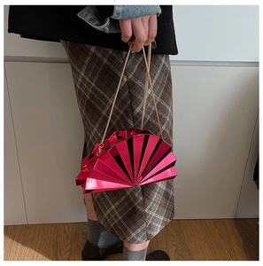 Detail of rose pink fan-shaped evening bag with metallic finish and gold chain strap