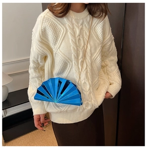 Blue fan-shaped acrylic clutch bag with gold chain strap worn by a female model