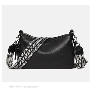 Detail of black lychee grain leather crossbody bag with geometric woven strap