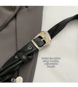 Detail of adjustable black leather strap with silver metal buckle and round charm