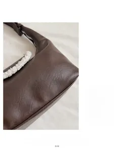 Gros plan d'un sac à main en cuir marron avec bordure en fausse fourrure blanche et grain fin