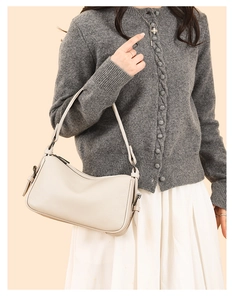 Close-up of beige lychee grain leather shoulder bag with adjustable strap and silver buckle