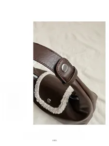 Détail du sac en cuir marron foncé avec bordure en fausse fourrure blanche et boucle