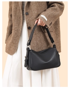 Detail of black lychee grain leather bag with silver buckle worn by a model in a suit