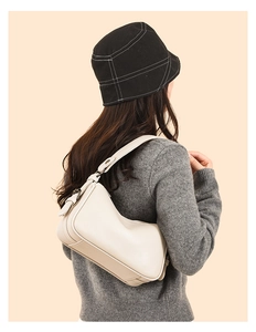Detail of creamy white leather hobo bag with pebble grain texture and wide strap