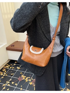 Gros plan du sac demi-lune en cuir marron avec bordure en sherpa blanc doux
