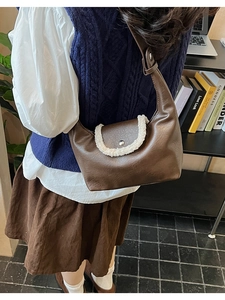 Détail du sac demi-lune en cuir marron avec bordure en fausse fourrure blanche et fermoir argent