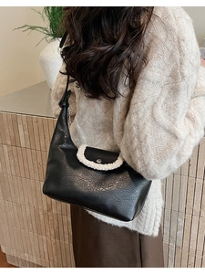 Sac hobo en cuir noir avec bordure en peluche blanche porté sur un pull beige