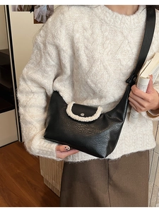Détail du sac à bandoulière en cuir noir avec bordure en polaire blanche contrastante