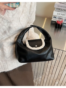 Détail du sac croissant noir avec bordure en fausse fourrure blanche et bouton argent