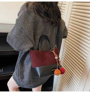 Detail of color-block tote bag featuring burgundy suede, black leather and charms