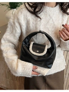 Détail du sac croissant en cuir noir avec bordure en fausse fourrure blanche et boucle métal
