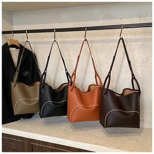Detail of four bucket bags in various colors hanging on a rack showing matte leather texture